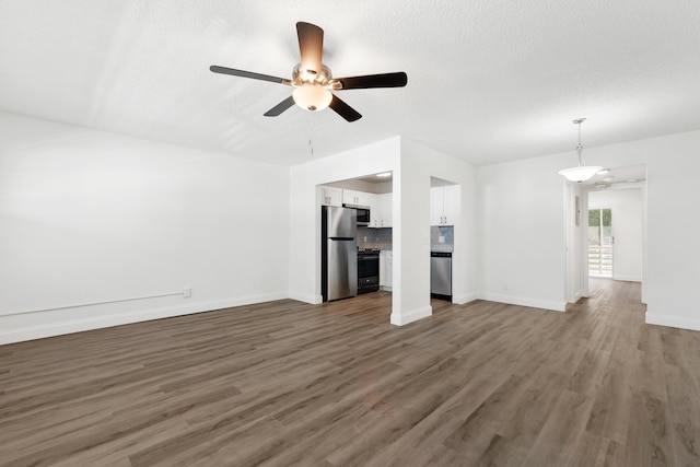 unfurnished living room featuring baseboards, a textured ceiling, ceiling fan, and wood finished floors