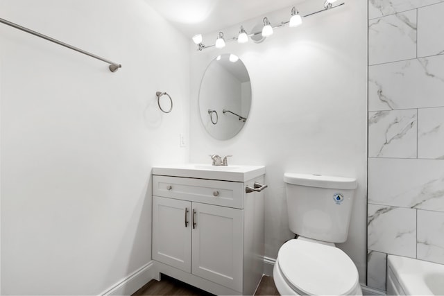 bathroom with toilet, vanity, and baseboards