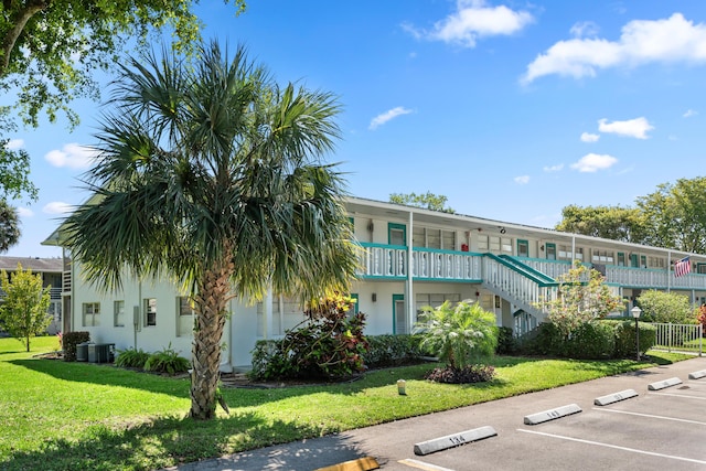 view of property with stairway, cooling unit, and uncovered parking