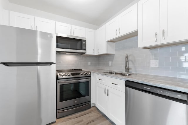 kitchen featuring a sink, white cabinets, light stone countertops, and stainless steel appliances