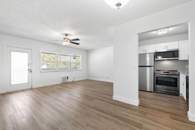 unfurnished living room with a textured ceiling, a ceiling fan, and light wood finished floors