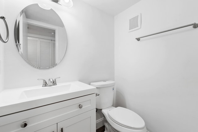 half bath with visible vents, toilet, and vanity