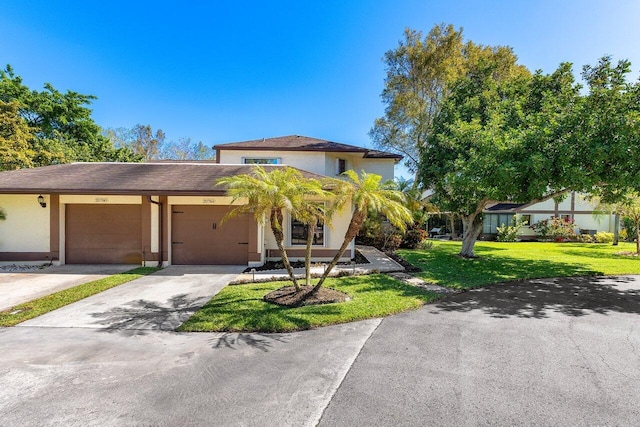 view of front of property with a front yard, an attached garage, driveway, and stucco siding