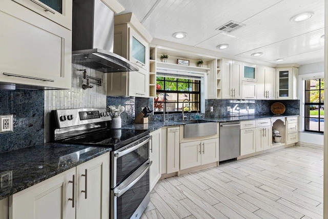 kitchen with visible vents, open shelves, a sink, appliances with stainless steel finishes, and wall chimney exhaust hood