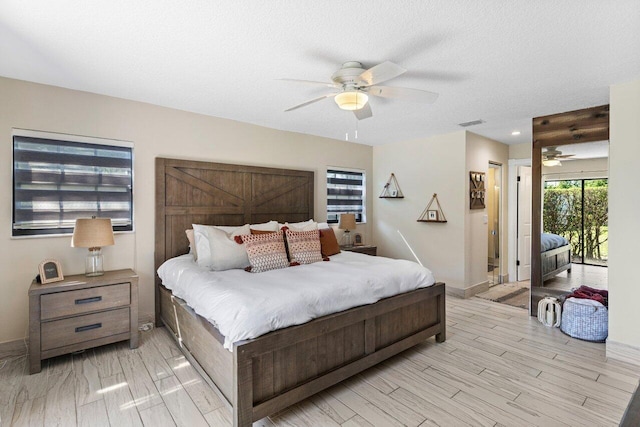 bedroom featuring a ceiling fan, baseboards, light wood-type flooring, and a textured ceiling