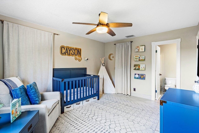 bedroom featuring a ceiling fan, baseboards, visible vents, a crib, and a textured ceiling