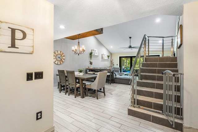 dining room with stairway, vaulted ceiling, ceiling fan with notable chandelier, wood finished floors, and a textured ceiling