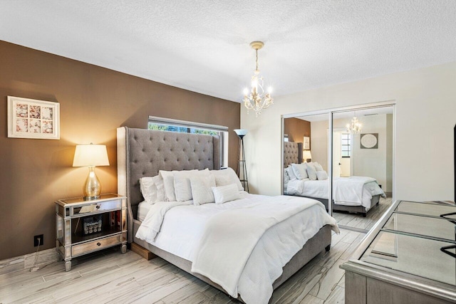 bedroom featuring light wood-type flooring, a textured ceiling, a closet, and a chandelier