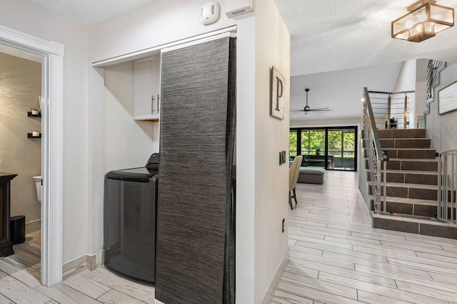 washroom featuring washer / clothes dryer, a textured ceiling, cabinet space, baseboards, and wood tiled floor