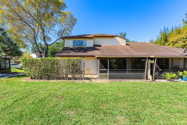 rear view of house with stucco siding, a lawn, and a sunroom