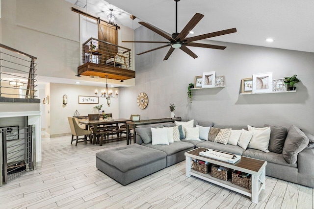 living area with recessed lighting, ceiling fan with notable chandelier, a fireplace, wood finished floors, and high vaulted ceiling