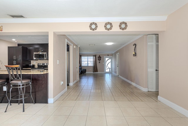 hallway featuring light tile patterned flooring, visible vents, crown molding, and baseboards