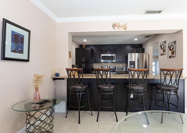 kitchen with visible vents, appliances with stainless steel finishes, a peninsula, and crown molding