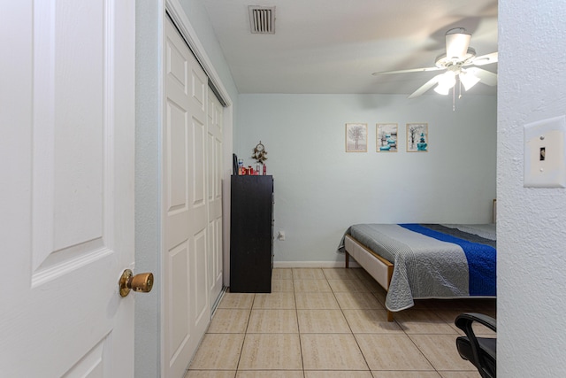 bedroom featuring visible vents, a closet, light tile patterned flooring, baseboards, and ceiling fan