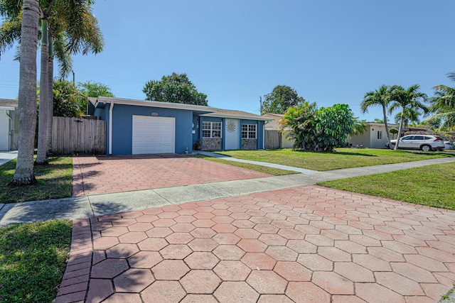 single story home featuring stucco siding, an attached garage, a front lawn, and fence