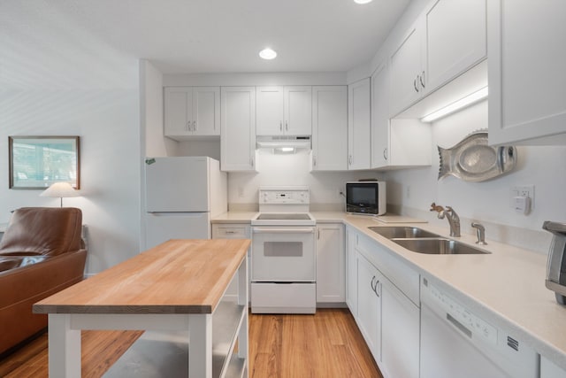 kitchen with light wood-style flooring, a sink, under cabinet range hood, white appliances, and butcher block counters