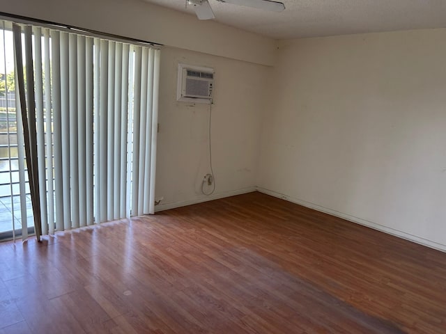 unfurnished room with ceiling fan, wood finished floors, and a wall unit AC