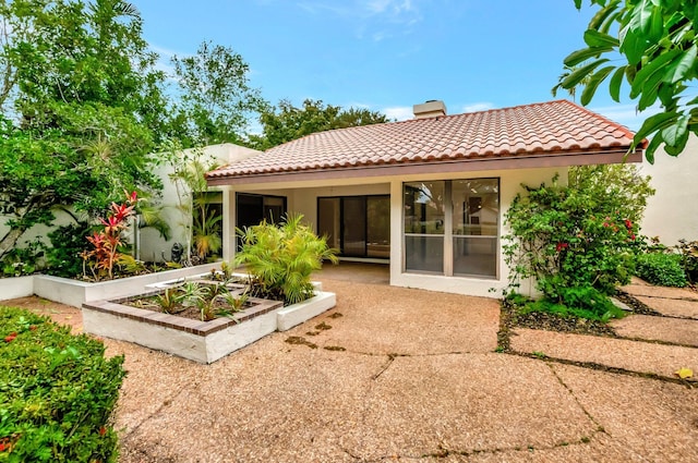 6740 Lago Vista Ter, Boca Raton, FL 33433 - back of house with a tile roof, stucco siding, a chimney, a garden, and a patio area