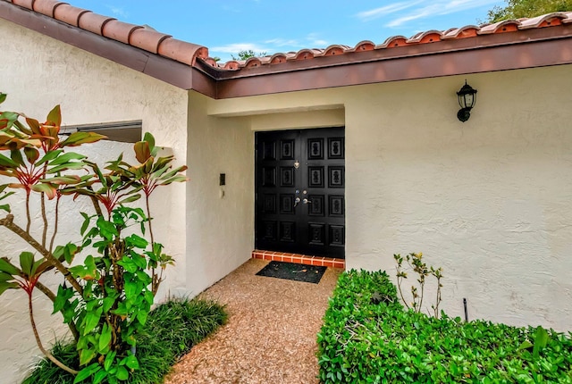 doorway to property with stucco siding and a tiled roof