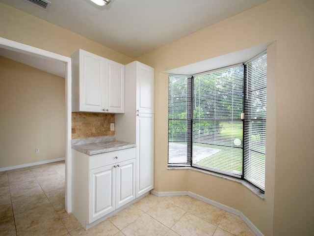 kitchen featuring decorative backsplash, white cabinetry, light countertops, and baseboards