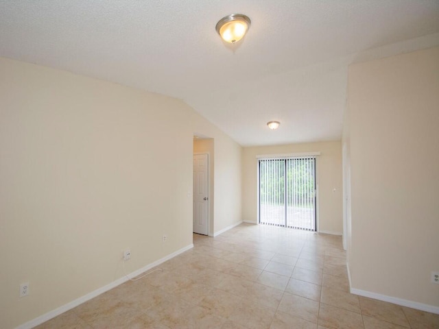 unfurnished room featuring light tile patterned floors, baseboards, a textured ceiling, and vaulted ceiling