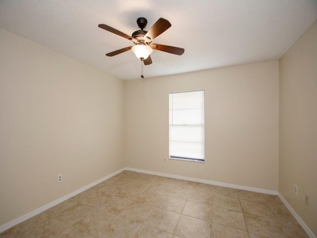 empty room with light tile patterned floors, baseboards, and a ceiling fan