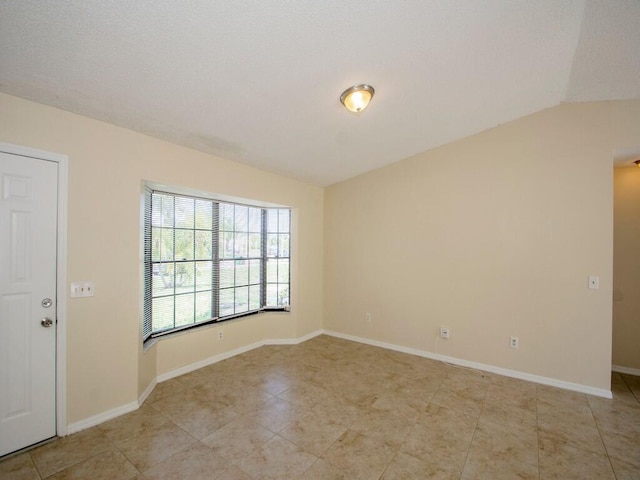 empty room featuring baseboards and vaulted ceiling