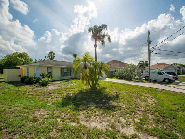 view of front of house featuring stucco siding, concrete driveway, and a front lawn