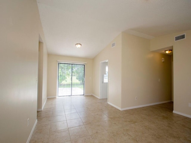 spare room with light tile patterned floors, visible vents, baseboards, and vaulted ceiling