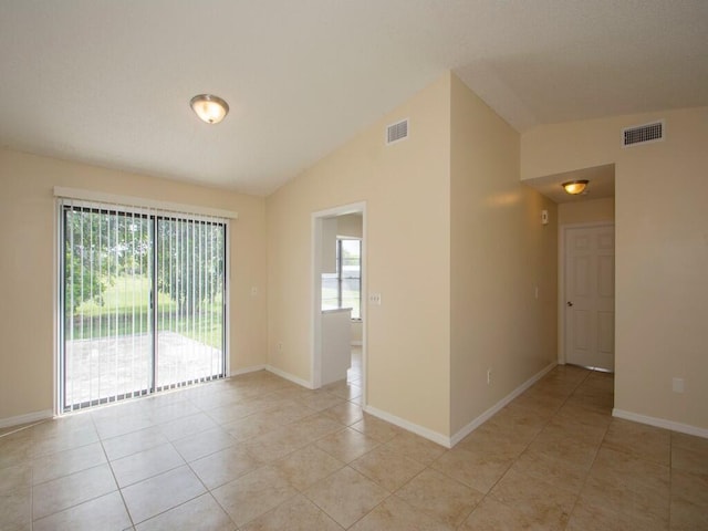 empty room with light tile patterned floors, visible vents, and lofted ceiling