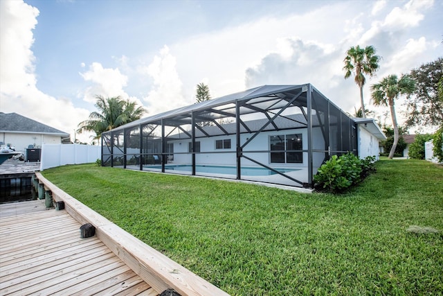 exterior space with glass enclosure, a yard, fence, and an outdoor pool