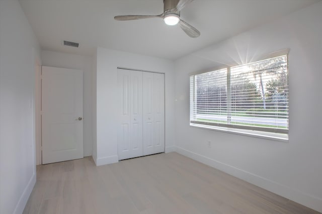 unfurnished bedroom with a closet, baseboards, visible vents, and light wood finished floors