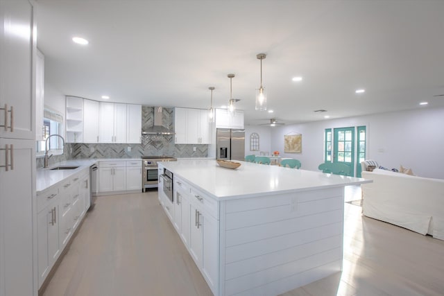 kitchen featuring open shelves, a sink, stainless steel appliances, wall chimney exhaust hood, and backsplash