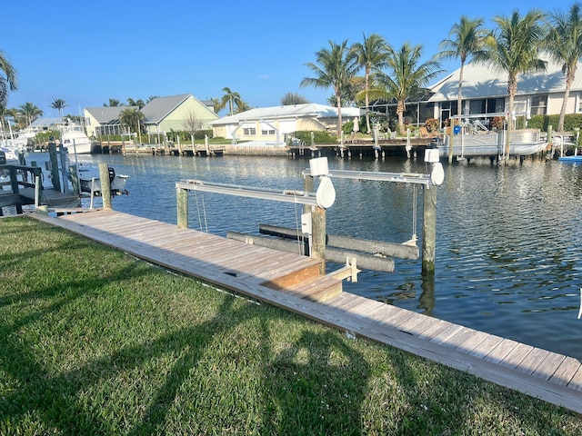 view of dock featuring a lawn, a water view, a residential view, and boat lift