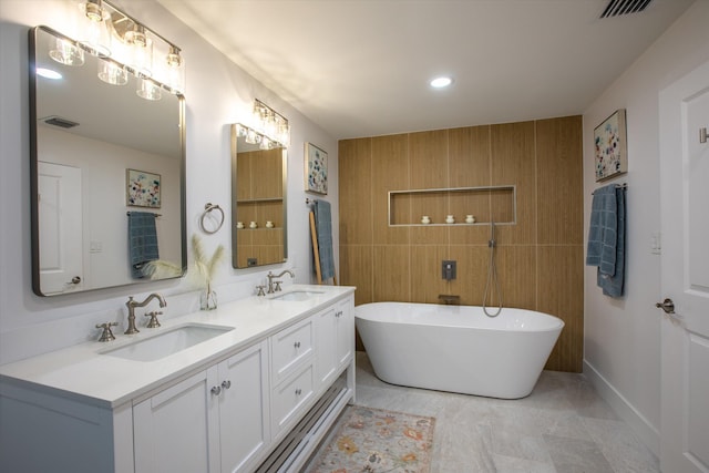 bathroom with a soaking tub, visible vents, and a sink