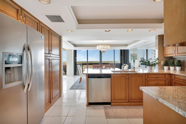 kitchen with visible vents, appliances with stainless steel finishes, a peninsula, a raised ceiling, and a sink