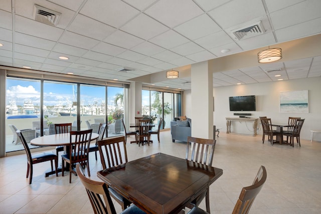 dining area with visible vents, a drop ceiling, and expansive windows