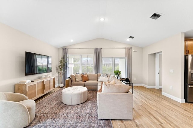 living room featuring visible vents, baseboards, light wood-style flooring, and vaulted ceiling