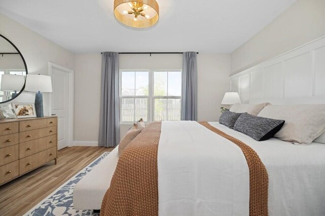 bedroom with a decorative wall and light wood-style flooring