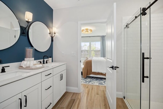 ensuite bathroom featuring a shower stall, wood finished floors, and a sink