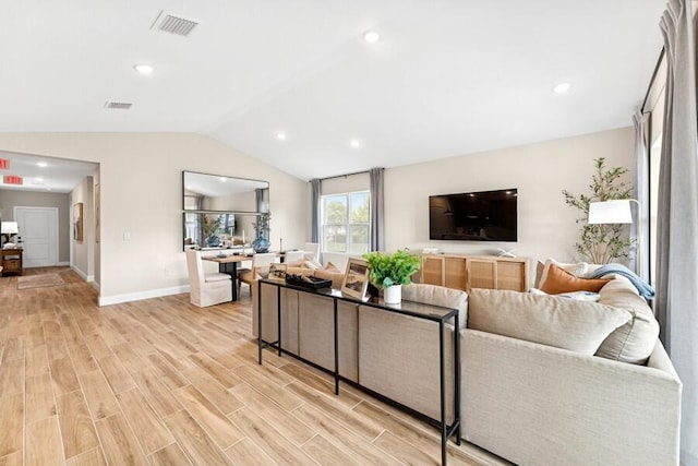 living room featuring visible vents, light wood-style flooring, baseboards, and vaulted ceiling