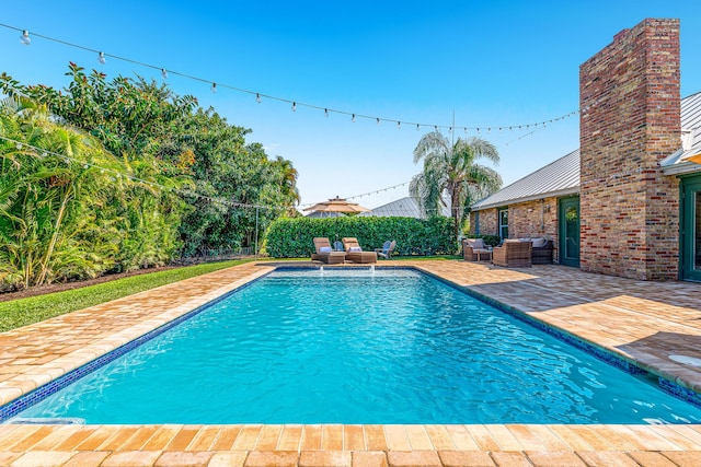 view of swimming pool featuring outdoor lounge area, fence, a patio area, and a fenced in pool