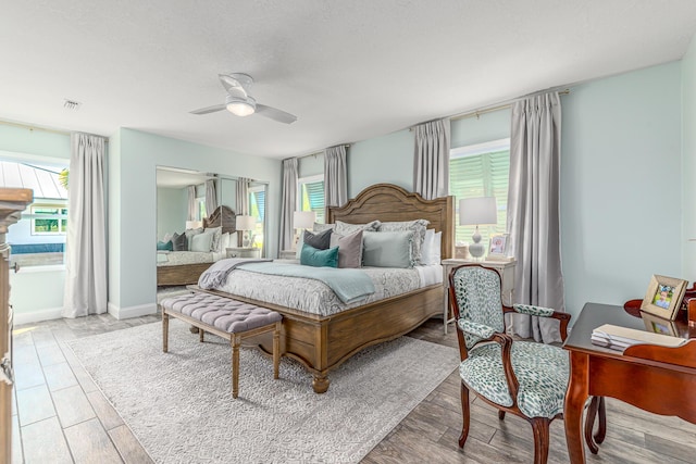 bedroom with visible vents, baseboards, ceiling fan, and wood finished floors