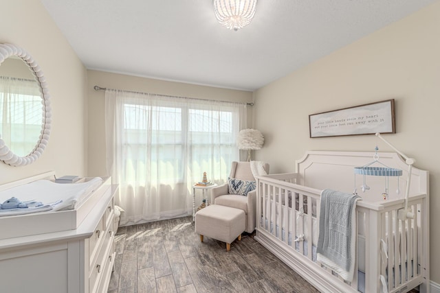 bedroom with a nursery area and wood finished floors