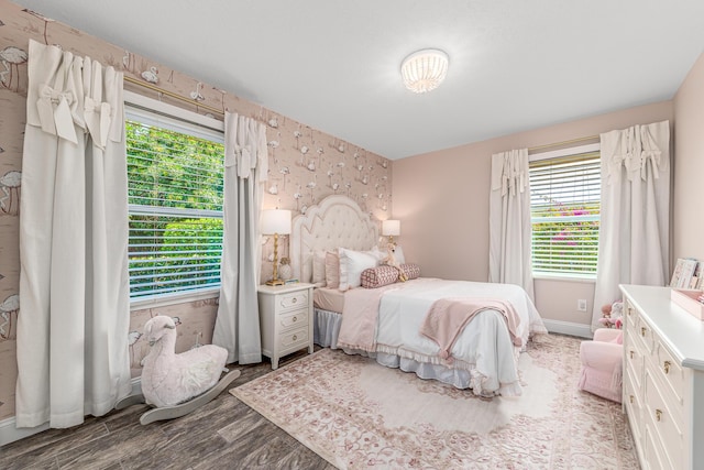 bedroom with wallpapered walls, wood finished floors, and baseboards