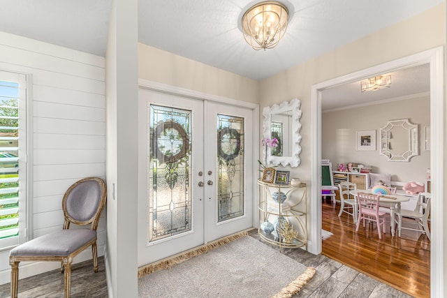 foyer featuring a chandelier, ornamental molding, french doors, and wood finished floors