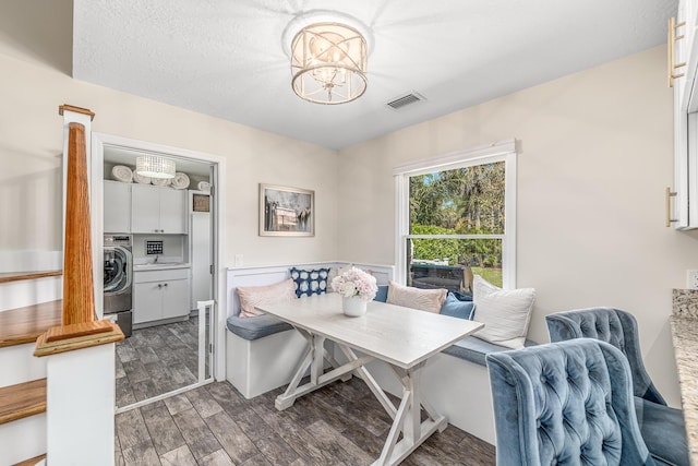 dining room with visible vents, wood finish floors, an inviting chandelier, washer / dryer, and breakfast area