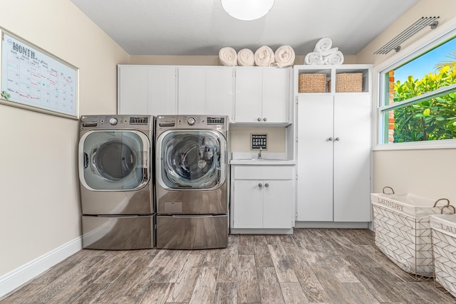 washroom with cabinet space, washing machine and dryer, baseboards, and wood finished floors