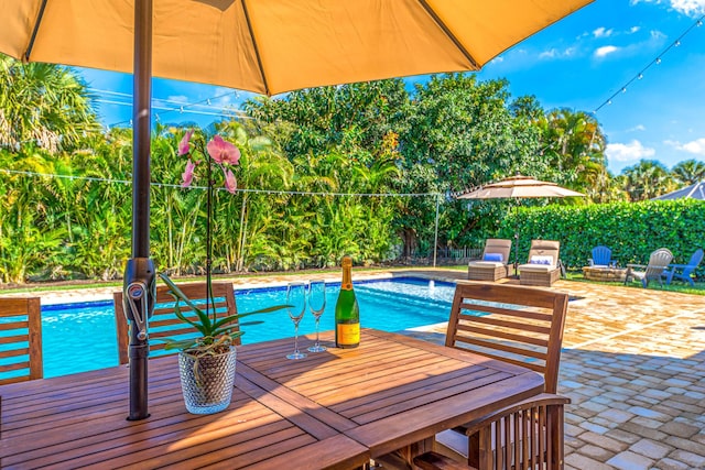 view of swimming pool with a patio, outdoor dining area, a fenced in pool, and fence