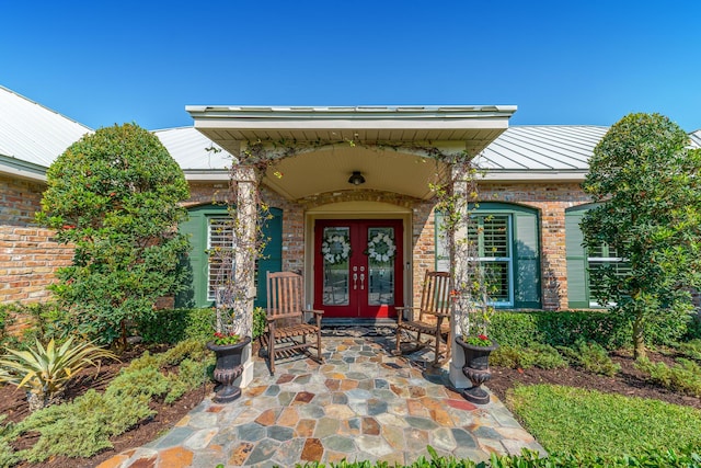 property entrance with brick siding, french doors, metal roof, and a standing seam roof